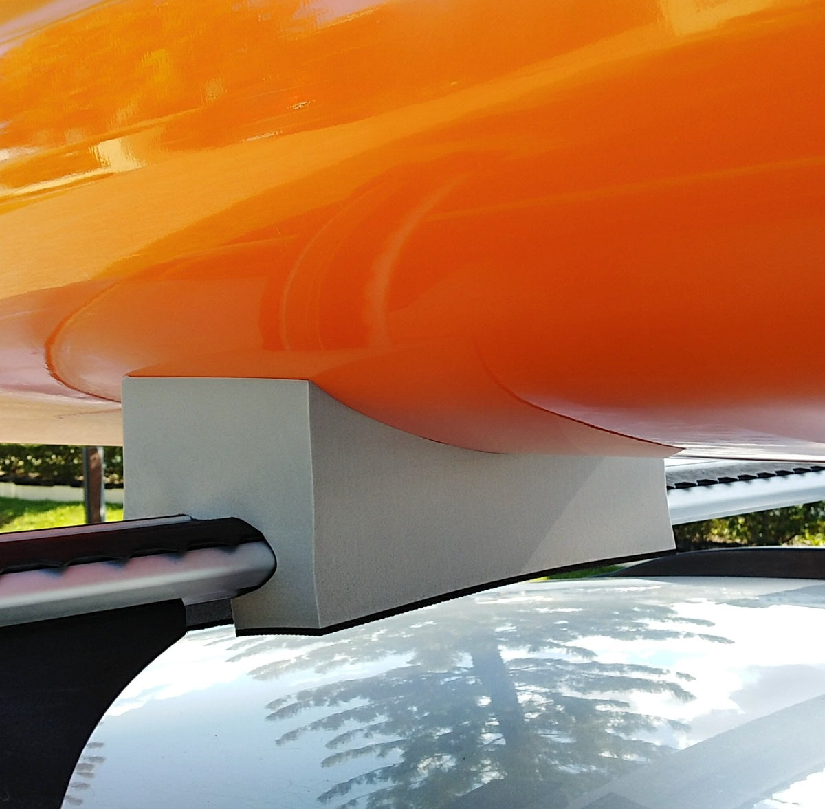 racing kayak supported by foam kayak mounts on car roof rack